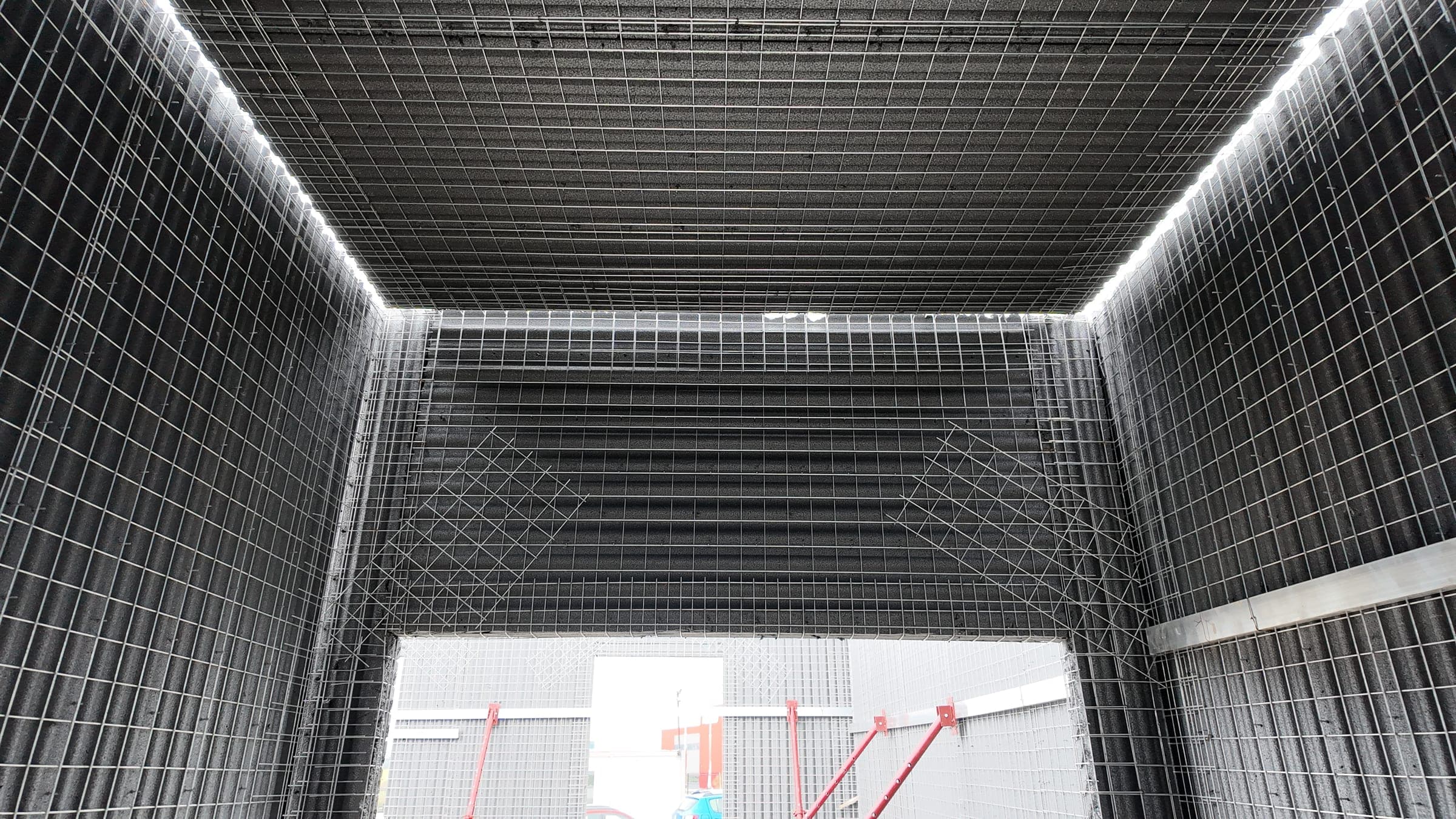 Steel-mesh panel walls around a door opening, with diagonal extra mesh above and at the corners.