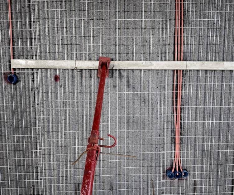 Orange electrical conduits and blue junction boxes placed inside the panel's mesh.